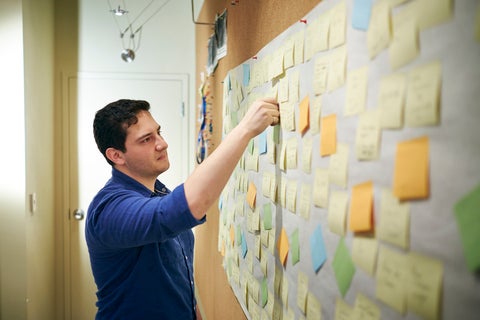 Graduate student placing sticky notes onto a wall to assist with studying