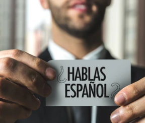 Business person holding sign "do you speak Spanish?".