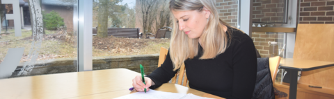 a student sitting at a table doing homework holding a pen