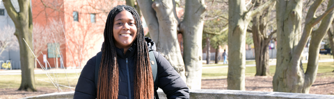 a student smiling standing on the bridge with trees in the background