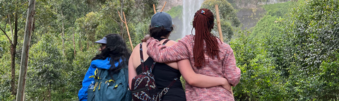 three people embracing and viewing a waterfall