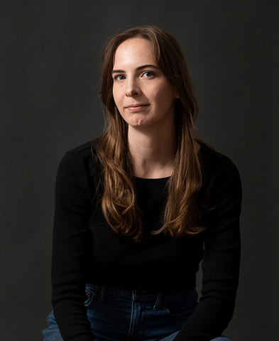 Colleen Dulle portrait, smiling in front of a grey background