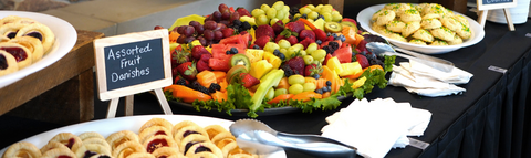 Plates of danishes, fruit, and cookies