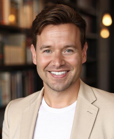 Matthew Durham smiles in a suit jacket and tie