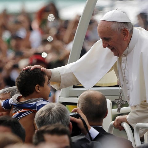 Pope Francis placing his hand on the head of a child in the crowd
