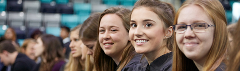 three students in their graduation robes smiling