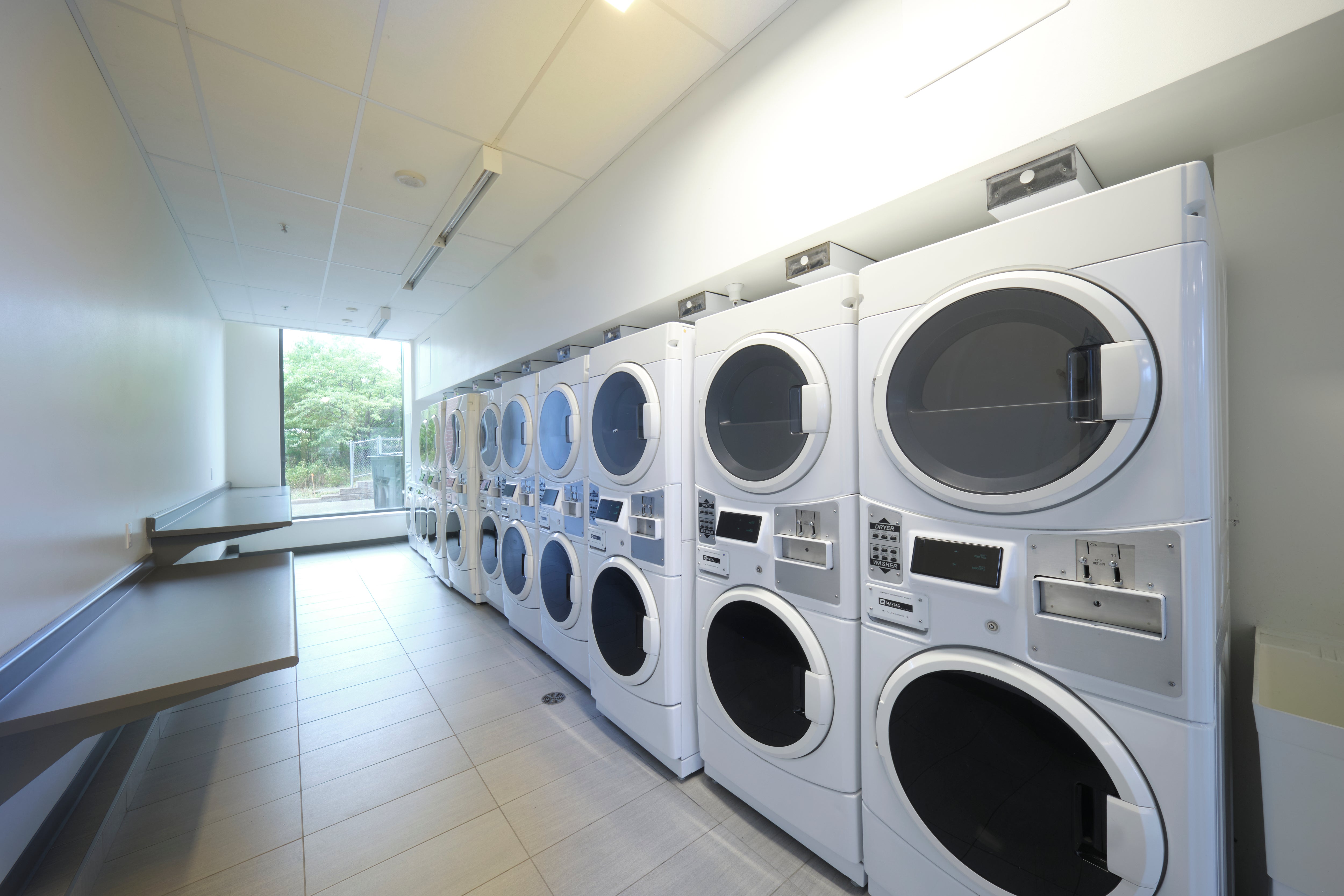 Laundry room with rows of stacked washers and dryers.