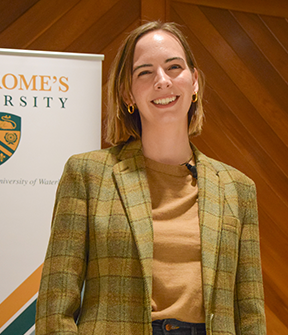 Colleen Dulle smiling at the camera from the stage at St. Jerome's University Chapel