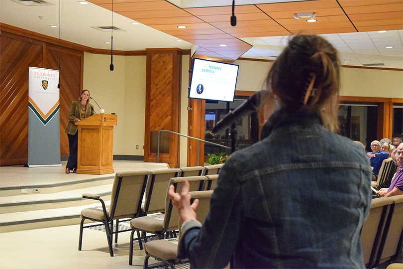 Colleen Dulle answers an audience member's questions while the audience member holds a microphone