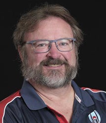 Dan Hutter smiling in front of a black background