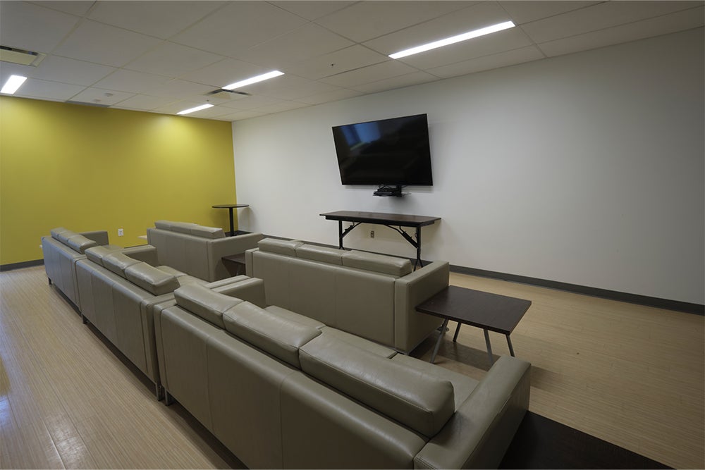 A room layout of the movie room in Siegfriend and Ryan Hall showing comfortable couches, end tables and tv.