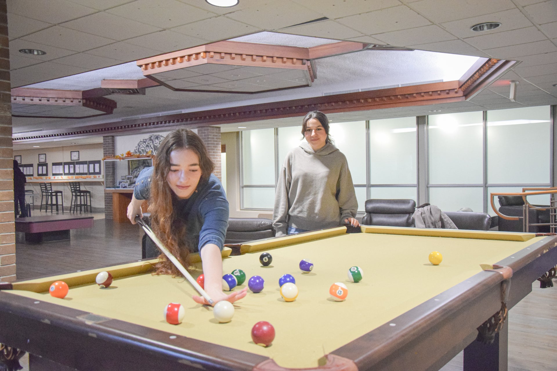 Two students playing pool in the fireplace lounge