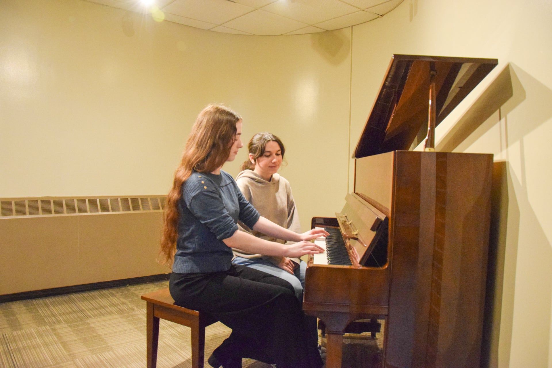 Two students singing and playing the piano in the music room
