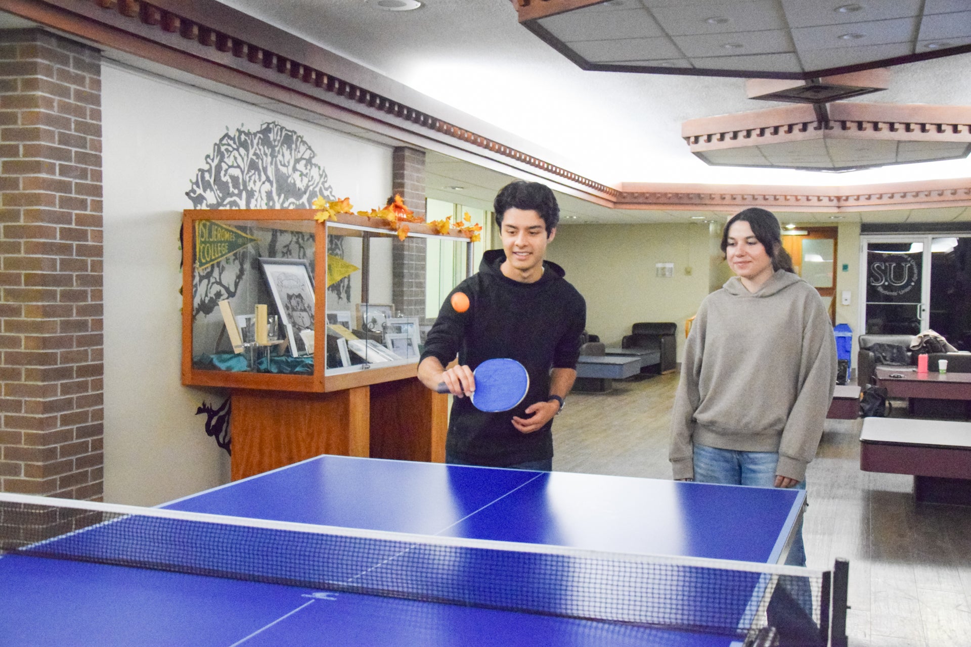 Two students playing ping pong in the Fireplace Lounge