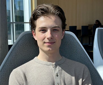 Cameron Fleming smiling in a grey buttoned sweater