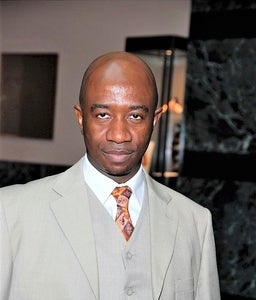 Dele Jemirade stands in from of a gallery wall