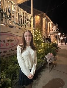 Emmelia Pitt stands in front of building decorated with fair lights.