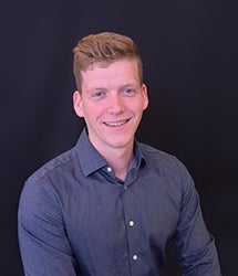 Jameson Olheiser portrait, smiling in front of a black background