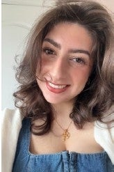 Jasmine Hermiz smiles in front of a neutral background