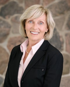 Mary Ellen smiles in front of a stone background