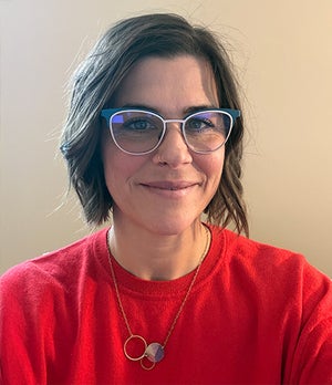 Melissa Chaffe smiling wearing a red t-shirt in front of a white background