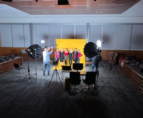 The Ops team at a film shoot with a yellow backdrop and film and lighting equipment.