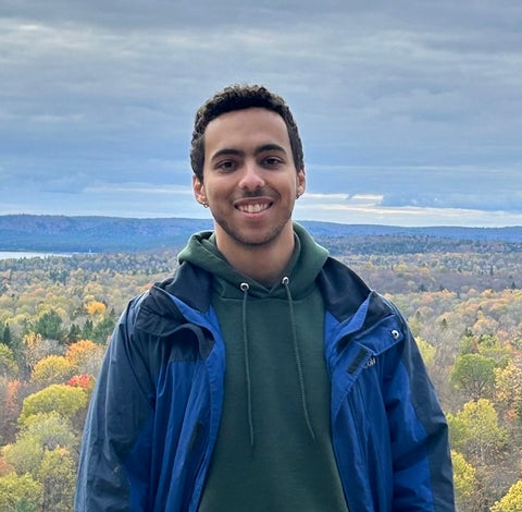 Nigel standing on a hill overlooking trees and water