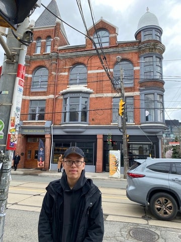 Yuqi standing in front of a large brick building. 