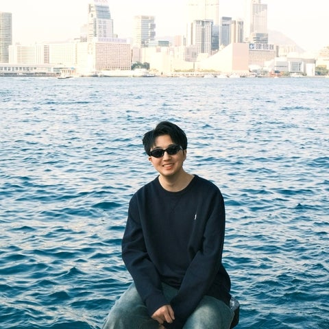 Zirui sitting in front of a river with city skyline in the background