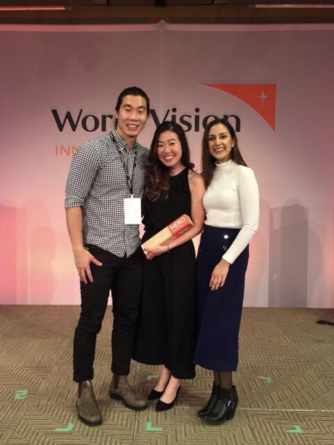 Cherie hold the award and poses with family members in front of a World Vision logo