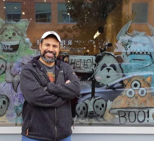 Jason Panda stands in front of a window mural he recently painted