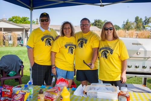 Gary Foerster, Lora Crestan, Don Herman and Val Foerster wearing yellow Warriors t-shirts with barbecue in the background