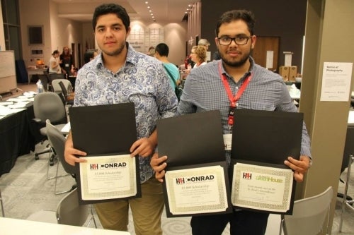 Zied and Moazam pose with three certificates 