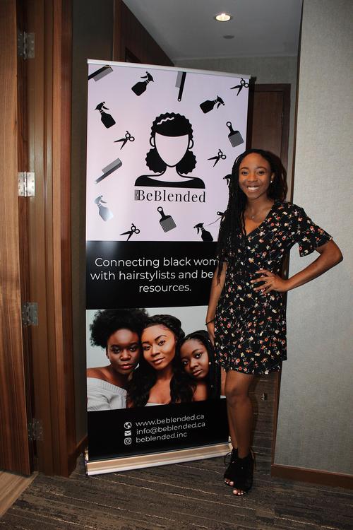 Aileen Agada stands in front of a pull-up banner promoting her venture BeBlended