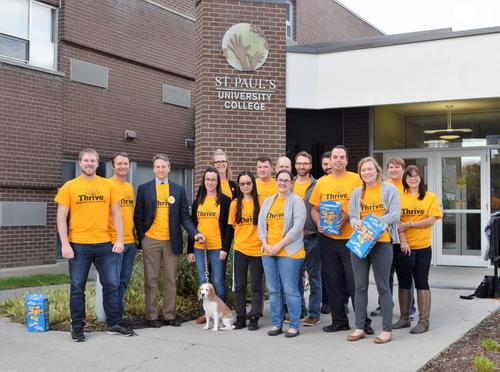 St. Paul's staff wearing yellow Thrive week t-shirts pose near the front entrance