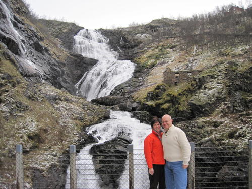 Anne and Andrew Grimson pose in front of a small waterfall