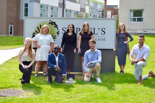 INDEV grads pose in front of the St. Paul's sign with buildings in the background