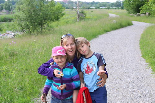 Julia Salvini hugging her two children with a walking trail in the background