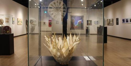 a glass case containing an Indigenous artifact with an art gallery in the background