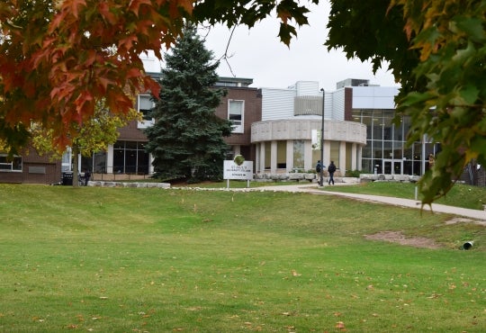 Exterior photo of St. Paul's with students walking toward the building and framed by fall foliage