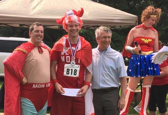 Sandy Clipsham, dressed as Captain Canada receives prize at Superhero Race for KidsAbility