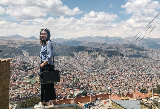 Cherie Wai stands on a ledge overlooking a panoramic view of the buildings of La Paz in Bolivia