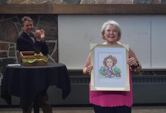 Mavis Fenn holds a framed caricature given as retirement gift