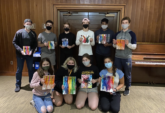 students wearing masks display their melted crayon artwork