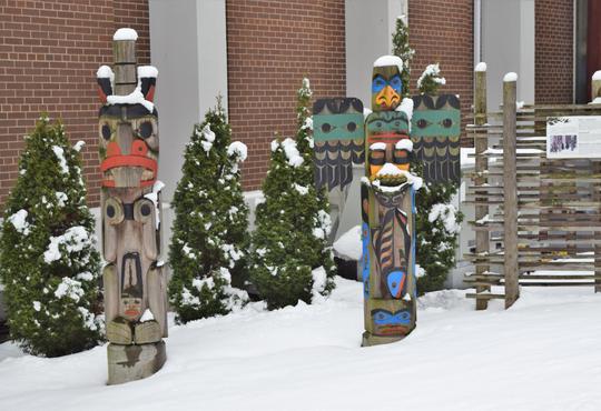 Two totem poles adorned with fresh snow