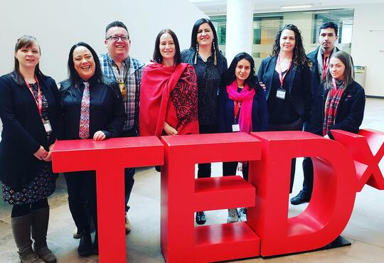 students and WISC staff posing with the red TEDx sign