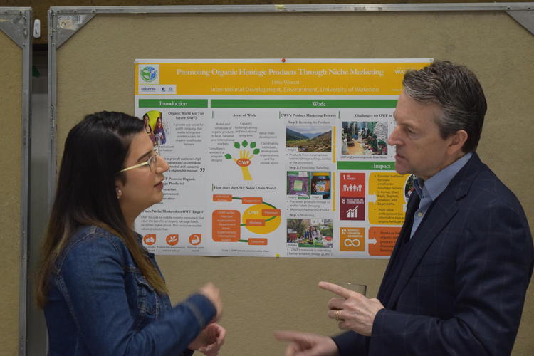 Rick Myers, right speaks with an INDEV student about her poster presentation at Capstone event