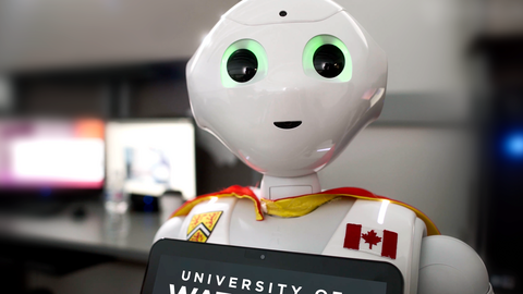 a humanoid robot wearing a University of Waterloo logo, Canadian flag, and a cape