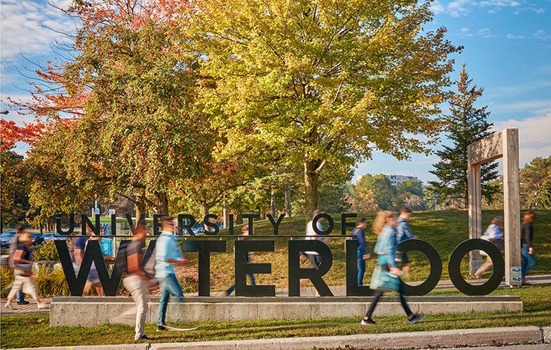 Students walk by Waterloo sign during fall.