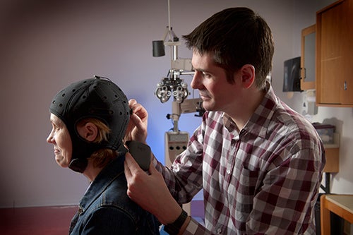 Ben Thompson adjusting an electrode on subjects helmet